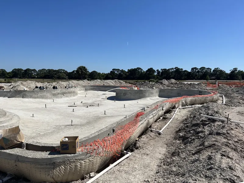 Excavated commercial pool shell with plumbing runs and rebar stubs in place