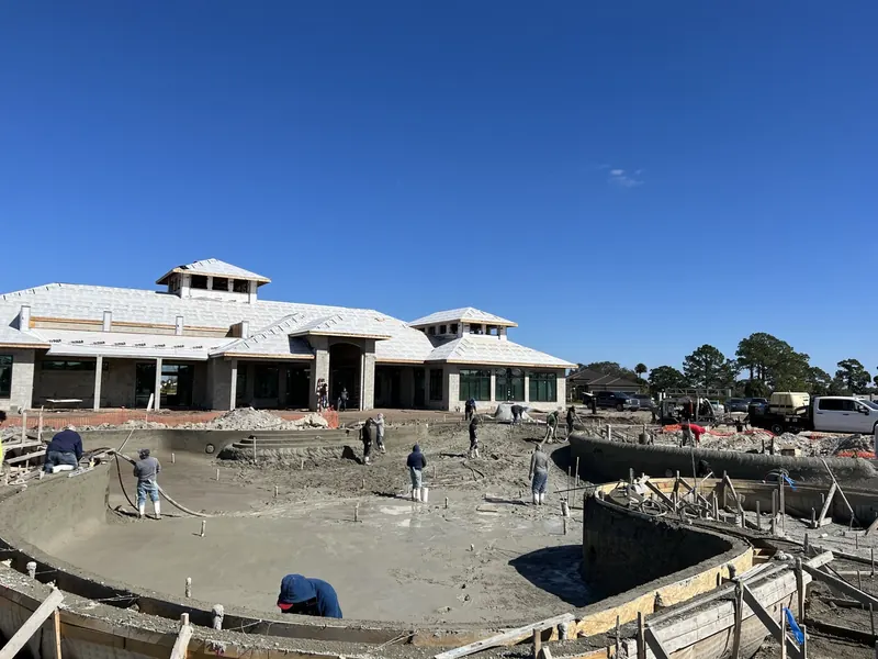 Crew shooting and shaping the gunite shell of a large commercial pool