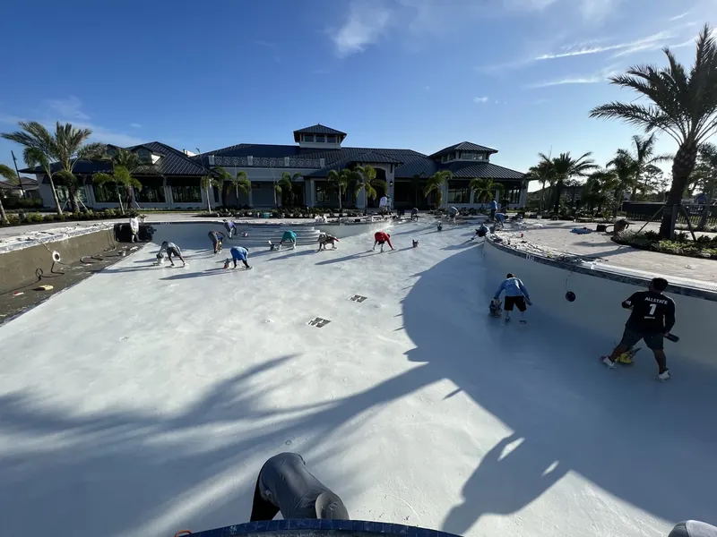 Large crew hand-troweling the interior plaster finish of a commercial pool